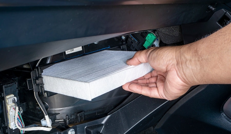 Technician replacing cabin filter in car